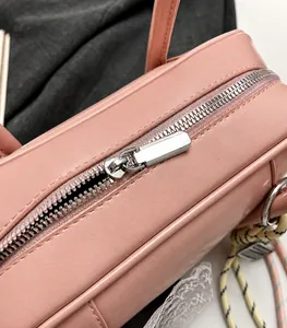 Close-up of smooth silver metal zipper and pink matte leather texture on a pillow bag