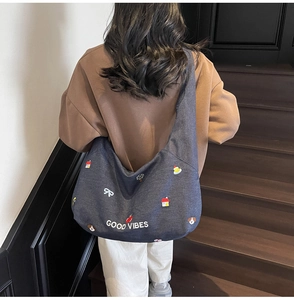 Dettaglio della borsa tote in denim blu con ricamo Good Vibes e toppe colorate sul retro