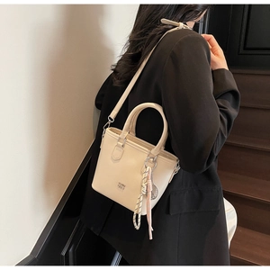 Détail d'un sac seau beige en cuir ciré avec foulard en soie et logo métallique