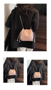 Detail view of pink drawstring bucket bag with chain strap on a model at stairs