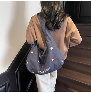 Dettaglio di una borsa tote in denim blu con ricami colorati e scritta Good Vibes
