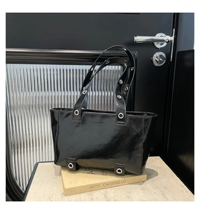Détail du sac cabas en cuir ciré noir brillant avec œillets métalliques et logo