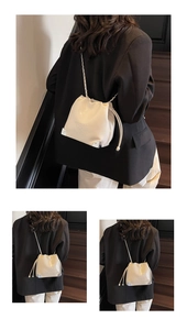 Detail of white drawstring bucket bag with silver chain strap and metal corner protectors