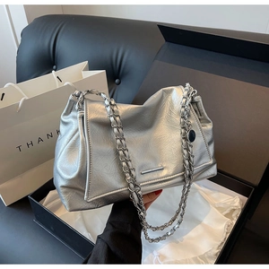 Détail du sac cabas argenté avec chaînes métalliques placé dans une boîte cadeau noire