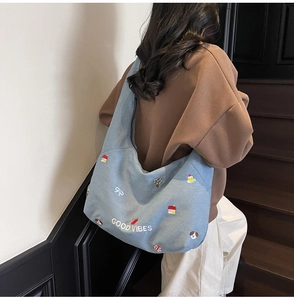 Dettaglio della borsa tote in tela azzurra con ricamo Good Vibes e motivi graziosi