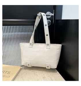 Vue détaillée du sac cabas blanc crème avec œillets métalliques suspendu à une porte