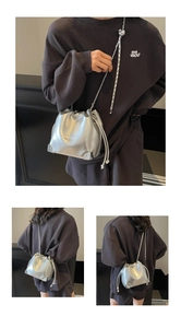 Close-up of silver bucket bag with chain strap showing metallic texture and brand engraving