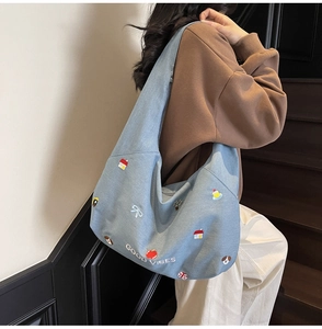 Dettaglio di una borsa tote in denim blu con ricami colorati e scritta Good Vibes ricamata
