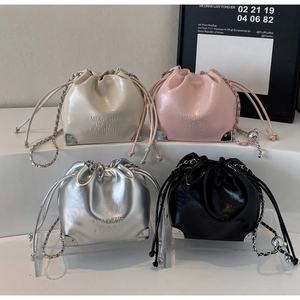 Detail of multi-color drawstring bucket bags with chain straps and metal corners