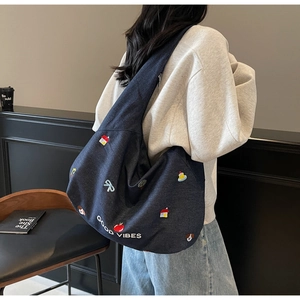 Dettaglio della borsa denim blu scuro con ricami colorati e scritta 'GOOD VIBES'