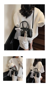 Detail view of black Boston bag with white lace bow and tennis racket charm accessory