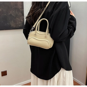 Close-up of cream bowling bag in lychee texture styled with a black top and white skirt