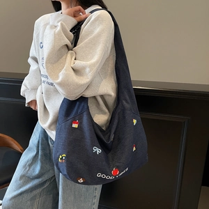 Dettaglio dei motivi ricamati e testo Good Vibes su una grande borsa tote in denim blu