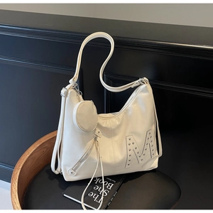 Detail of off-white glossy leather tote bag with M-studs and mini round coin purse charm