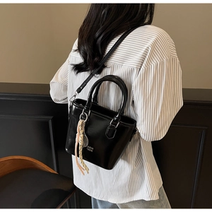 Détail d'un sac seau en cuir ciré noir avec poignées et un charme en corde tressée