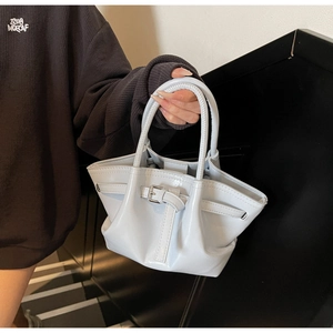 Detail der hellblauen Lackleder-Beuteltasche mit gewebtem Griff und Schnallendetail