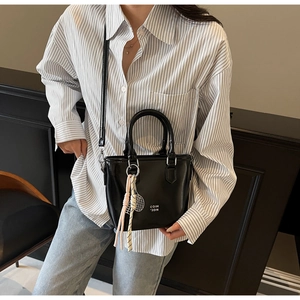 Détail du sac seau en cuir ciré noir avec logo blanc et breloque raquette de tennis