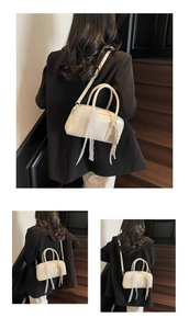 Detail of cream white Boston bag with lace bow charm and adjustable crossbody strap