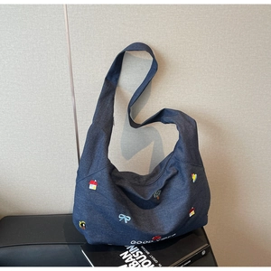 Dettaglio della borsa hobo in denim blu con toppe ricamate e scritta Good Vibes