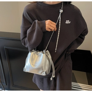 Silver mirror bucket bag with metallic chain and adjustable ball shown on a model