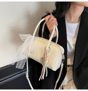 Detail of off-white leather pillow bag with lace bow and woven tennis racket pendant