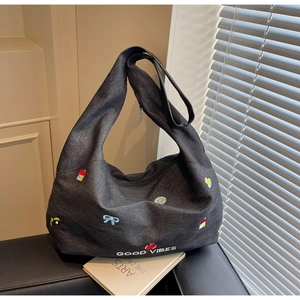 Dettaglio della borsa tote in denim grigio con toppe ricamate e scritta Good Vibes