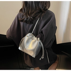 Detail view of silver chain bucket bag with drawstring closure and metal corners