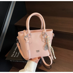 Détail du sac seau en cuir ciré rose clair avec breloque raquette de tennis et foulard en soie