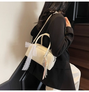 Detail of off-white boston bag featuring lace ribbon and woven strap for shoulder carry