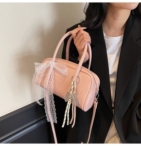 Detail of pink Boston bag with lace bow charm and polished leather finish