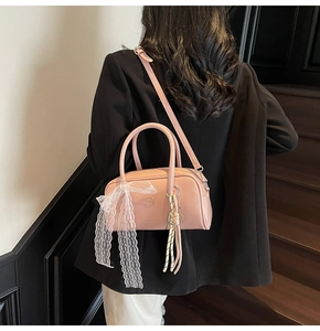 Pink pillow bag with lace bow and woven pendant details shown on a black suit model