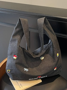 Borsa tote in denim grigio scuro con ricami colorati e scritta Good Vibes su legno
