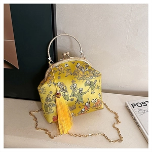 Détail du sac à main brodé en soie jaune avec motifs traditionnels et pompon doré