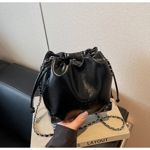 Detail shot of black drawstring bucket bag with silver chain strap and metal corners