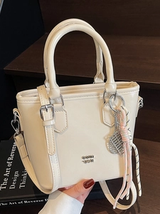Sac seau chic en cuir blanc crème avec charm raquette de tennis et logo sur escalier sombre