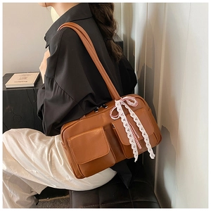 Detail of a brown bowling bag with two front flap pockets and white lace ribbon decoration