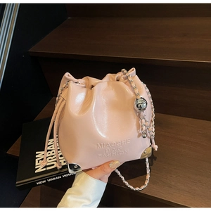 Detail of pink patent leather bucket bag with silver chain strap and drawstring closure