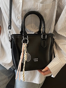 Sac seau minimaliste en cuir ciré noir avec charm raquette et logo argenté élégant