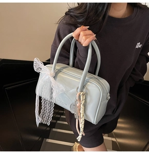 Detail of light blue patent leather Boston bag with white lace bow and tennis charm