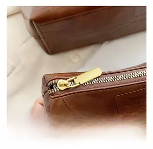 Dettaglio della borsa tote marrone vintage con stampa coccodrillo e cerniera in metallo