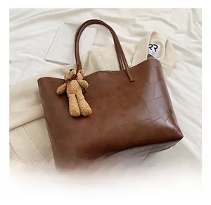 Dettaglio della borsa tote in ecopelle marrone con texture patchwork e orsetto