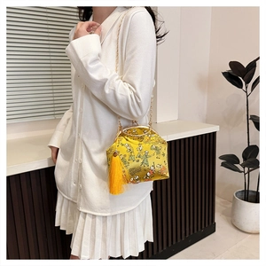 Détail du sac brodé jaune avec fermoir métallique, pompon en soie et chaîne dorée
