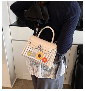 Detail of checkered square handbag with colorful flower patches and silver twist lock