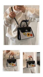 Detail of floral embroidery on a black and white grid crossbody bag with metal lock