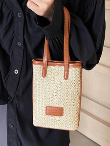 Vertical straw woven tote bag with brown leather trim and handles for summer beach style