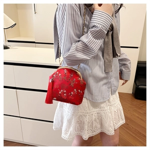 Détail du sac en satin rouge avec fermoir doré et gland long sur bandoulière chaîne
