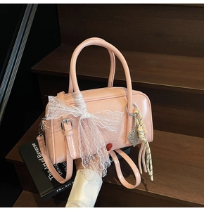 Close-up of pink patent leather pillow bag with white lace bow and decorative charms