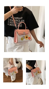 Detailed view of pink plaid square bag featuring floral appliques and a top handle
