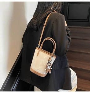Détail d'un sac seau bicolore beige et kaki avec un charme de dessin animé et une bandoulière