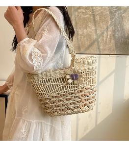 Close-up of handmade straw bucket bag with purple bow charm and lace dress details